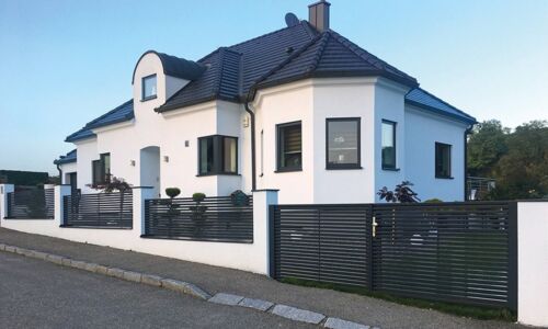 Einfamilienhaus mit Aluzaun und Flügeltor an der Straße 