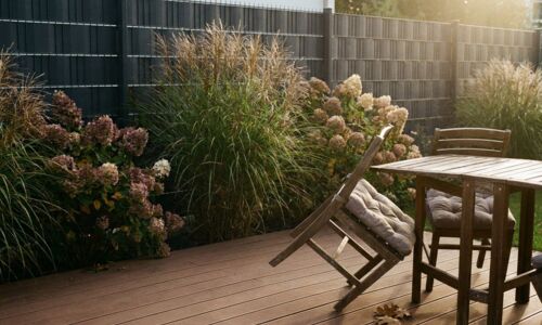 Terrasse mit WPC-Dielen, dahinter ein Sichtschutzzaun in Anthrazit Terrasse und Zaun in einer Linie gedacht: Erst dadurch wird aus zwei Bauteilen ein Raum